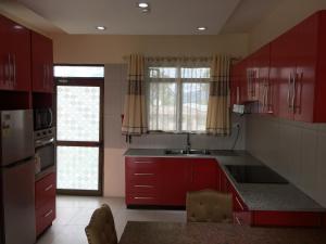 a kitchen with red cabinets and a sink and a window at Bhan Towers Apartment in Suva