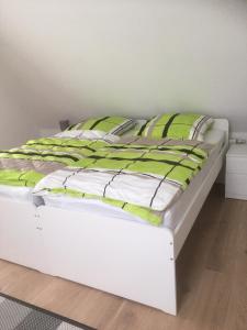 - un lit blanc avec des draps et des oreillers verts et blancs dans l'établissement Ferienwohnung Bruni I, à Oldenbourg