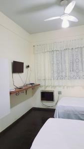 a bedroom with a bed and a tv and a window at Falcon Hotel in Bauru