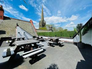 a patio with picnic tables and a church in the background at PHOENIX Executive Apart-Hotel in Goole