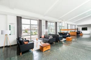 una gran sala de estar con sofás, mesas y ventanas. en Hotel Akazienhaus, en Herzogenaurach