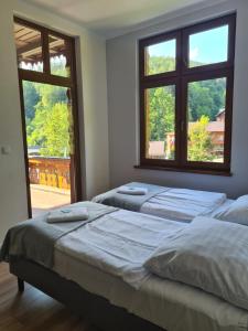 two beds in a room with two windows at Willa Góralka in Miedzygorze