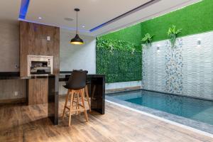 a kitchen with a pool and a bar with a stool at Drops Motel Manaus in Manaus