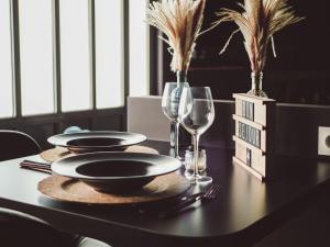 a table with two plates and wine glasses on it at Atelier du chill - Bergues in Bergues