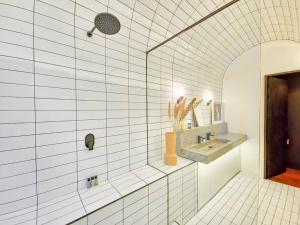 a white tiled bathroom with a sink and a mirror at New York Style Apartment with the City Life! in Cape Town