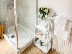 a bathroom with a shower and a white shelf with towels at Waverley Lodge - Quaint Victorian Home With Free Parking in York