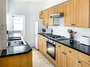 a kitchen with wooden cabinets and a stove top oven at Waverley Lodge - Quaint Victorian Home With Free Parking in York