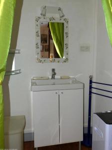 een badkamer met een witte wastafel en een spiegel bij La Demeure d'Eugénie 