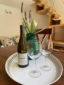 a bottle of wine and two wine glasses on a plate at Gîte l'Ouvèze in Roaix