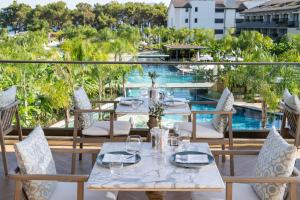 een patio met tafels en stoelen en een zwembad bij Akra Fethiye The Residence Tui Blue Sensatori - Ultra All Inclusive - Adults Only in Fethiye