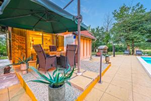 ein Haus mit einem Tisch, Stühlen und einem Sonnenschirm in der Unterkunft Villa Suzana's Nature Hideout in Gospić