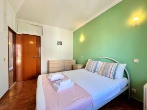 a green bedroom with a bed with towels on it at Albufeira Classic 2 by Homing in Albufeira