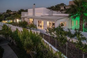 a house with a fence and palm trees at night at Felix Villa with magic view in Ayía Paraskeví
