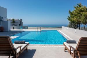 a swimming pool with two chairs and the ocean at Felix Villa with magic view and heated pool in Ayía Paraskeví