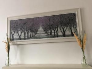 a painting of trees with two vases on a shelf at Spacious 3 bedroom house can sleep 6 in Leeds