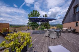 une terrasse en bois avec une table et un parasol dans l'établissement Das Arni´s, à Mehlmeisel