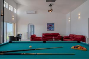 a living room with a pool table and red couches at Felix Villa with magic view and heated pool in Ayía Paraskeví