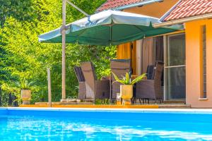 a group of chairs and an umbrella next to a swimming pool at Villa Suzana's Nature Hideout in Gospić