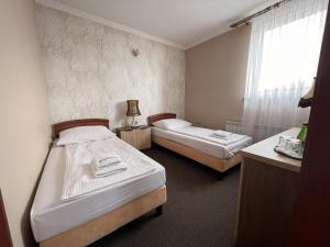 2 Betten in einem kleinen Zimmer mit Fenster in der Unterkunft Noclegi-Restauracja Boss in Mogilno