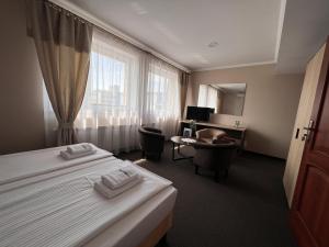 a hotel room with two beds and a desk at Noclegi-Restauracja Boss in Mogilno