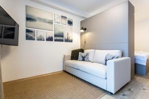 a living room with a white couch and pictures on the wall at Klínovec-Apartments in Loučná pod Klínovcem