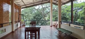 une terrasse couverte avec des chaises et des tables ainsi qu'un balcon arboré dans l'établissement Me-Family, à Matale