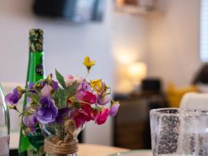 a vase of flowers on a table next to a bottle at Suncroft in Port Isaac