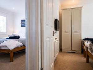 a bedroom with a bed and a tv and a door at Suncroft in Port Isaac
