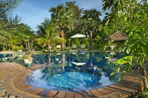 a swimming pool in a resort with palm trees at Battambang Resort in Battambang