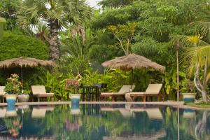 a swimming pool with chairs and umbrellas and trees at Battambang Resort in Battambang