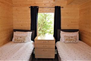 two twin beds in a cabin with a window at Stunning 5-Bed Cabin in Ashton Under Hill in Evesham