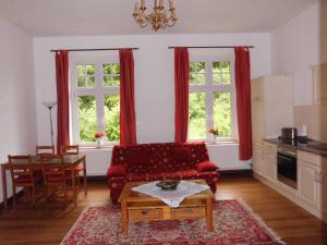 a living room with a red couch and two windows at Gutshaus Wohlenhagen in Wohlenberg