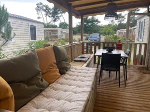 un canapé sur une terrasse avec une table et une table dans l'établissement Mobil home au calme au Cap-Ferret - Camping en première ligne du bassin, à Lège-Cap-Ferret