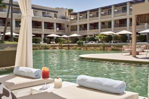 Atlantica Kalliston Resort - Adults Only في ستالوس: مسبح الفندق مع طاولة مع شمعة و شراب