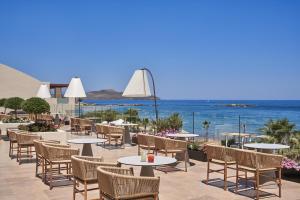 a patio with tables and chairs and the ocean at Atlantica Kalliston Resort - Adults Only in Stalos