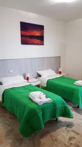 dwa łóżka z zieloną pościelą w pokoju w obiekcie Happy House w mieście Coppito