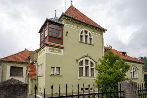 une grande maison jaune avec une clôture noire dans l'établissement Clasic Haus Sighisoara, à Sighişoara