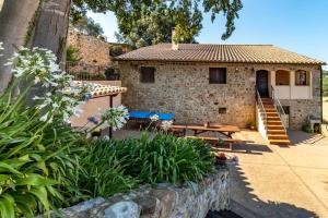 una casa de piedra con una mesa de picnic delante de ella en Mas Roca Casa rural en entorno único en Girona