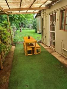 d'une terrasse avec une table en bois et de la pelouse verte. dans l'établissement Lovely 1 Queen bed, 1 Sleeper couch Self-catering cottage, à Kloof