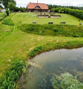 a pond in the middle of a field with a house at Viesu nams Vālodzes in Sigulda