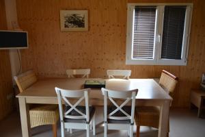 a dining room table with chairs and a wooden wall at Beautiful lake view 3 bedroom chalet. in Saint-Manvieu-Bocage