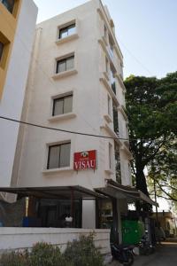 a tall white building with a sign on it at Hotel Visau,Shirdi in Shirdi