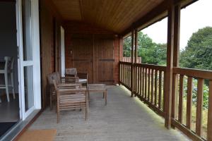 a porch of a cabin with chairs and a table at Beautiful lake view 3 bedroom chalet. in Saint-Manvieu-Bocage