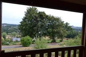 a view of a large tree from a window at Beautiful lake view 3 bedroom chalet. in Saint-Manvieu-Bocage