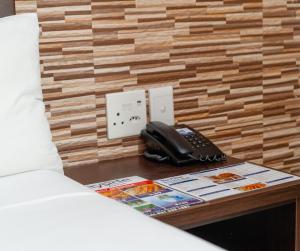 ein Telefon auf einem Tisch neben einem Bett in der Unterkunft Bayside Hotel 100 Pixley Kaseme Street (West Street) in Durban