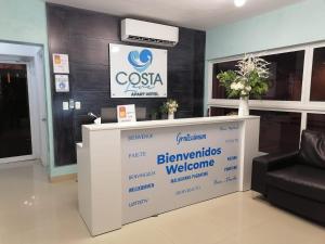 a reception desk in a lobby with a sign at Costa Love Aparta Hotel in Punta Cana