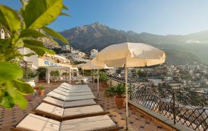 a row of lounge chairs with an umbrella on a balcony at Hotel Conca d'Oro in Positano