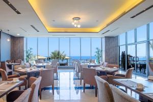 Waves Hotel في أملج: مطعم به طاولات وكراسي ومطل على المحيط