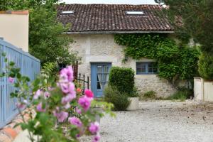 a stone house with a blue door and pink flowers at Domaine Les Granges in Saint-Jean-dʼAngély