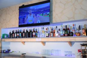 - une télévision sur un mur au-dessus d'un bar avec des bouteilles d'alcool dans l'établissement Blue Birds International Hotel, à Addis-Abeba